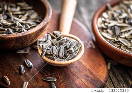 Sunflower Seeds in Wooden Spoon With Bowls on Rustic Cutting Board, Close-Up Texture 138925389