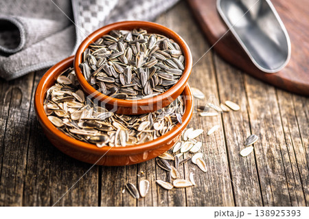 Sunflower Seeds in Bowl on Wooden Table With Scattered Shells Rustic Snack Background 138925393