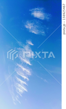 Delicate white wispy cirrus clouds forming a diagonal pattern against a vibrant clear blue sky. 138925467