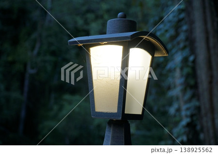 Black lamp post with a white shade is lit up 138925562