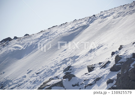 Snow covered mountain with a rocky slope Snow covered mountain with a rocky slope 138925579