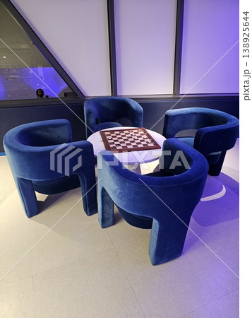 Blue chair is next to a white table with a checkered board 138925644