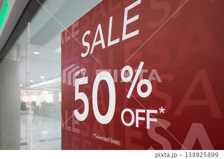 Red sale sign on store window offering up to fifty percent off 138925899