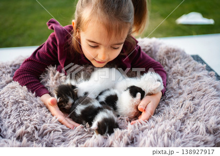 Little girl holding and caring for small kittens outdoors 138927917