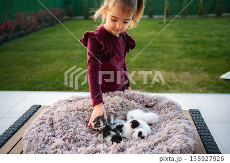 Girl bonding with newborn kittens on fluffy blanket outdoors 138927926