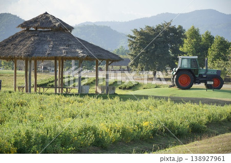 Tractor is in a field next to a pavilion 138927961