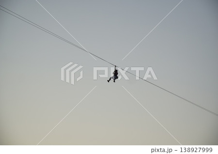 Man is zipping through the air on a zip line Man is zipping through the air on a zip line 138927999