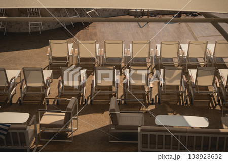 Rows of Empty Sun Loungers Under the Shade in a Relaxing Poolside Setting with a Calm Atmosphere and Warm Natural Light Rows of Empty Sun Loungers Under the Shade in a Relaxing Poolside Setting with a Calm Atmosphere and Warm Natural Light 138928632