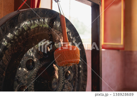 Intricate Detail of Traditional Gong Instrument with Wooden Mallet in Cultural Setting, Capturing Serenity and Sound in Artistic Composition 138928689