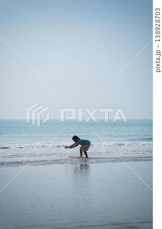 Child Playing on Beach at Sunrise, Joyful Moment of Discovery, Seaside Exploration, Tides and Waves, Nature and Childhood Happiness Child Playing on Beach at Sunrise, Joyful Moment of Discovery, Seaside Exploration, Tides and Waves, Nature and Childhood Happiness 138928703