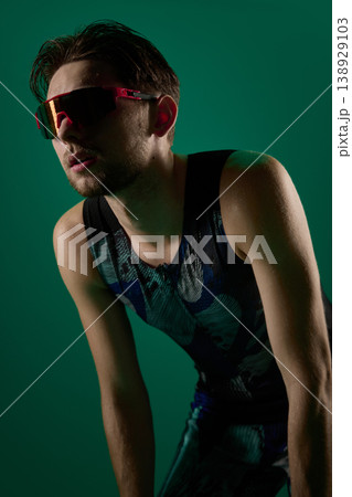 Close up of male athlete leaning forward resting after workout on green background 138929103