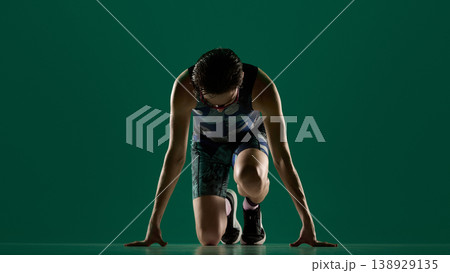 Male athlete kneeling in start position front view ready to run in studio. Male athlete kneeling in start position front view ready to run in studio. 138929135