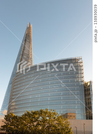 The Shard pierces the horizon as a soaring needle of glass, standing as a dominant silhouette against the sky. Beside it, the gracefully curved News Building reflects the sun golden glow, its rhythmic The Shard pierces the horizon as a soaring needle of glass, standing as a dominant silhouette against the sky. Beside it, the gracefully curved News Building reflects the sun golden glow, its rhythmic 138930039