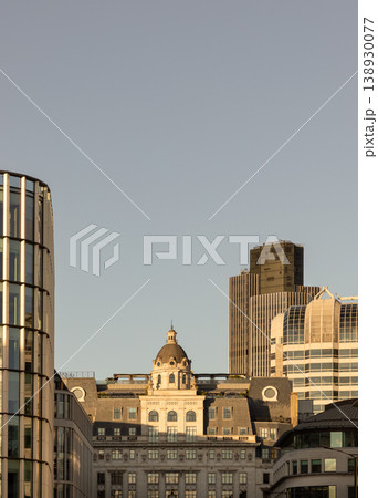 London skyline is a serene dialogue between heritage and ambition, bathed in golden evening light. At its heart, a classical stone building with a stately dome stands with timeless poise. Framing this 138930077