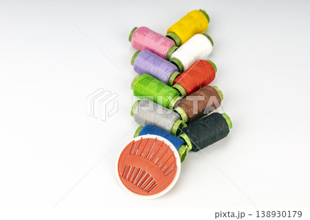 Assorted Colorful Thread Spools Arranged with Orange Pincushion and Hand Sewing Needles Assorted Colorful Thread Spools Arranged with Orange Pincushion and Hand Sewing Needles 138930179