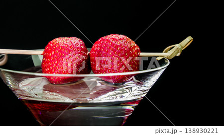 Strawberries garnishing martini cocktail drink on black background 138930221