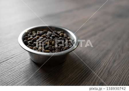 Close up cat dry food in metal bowl on wooden table 138930742