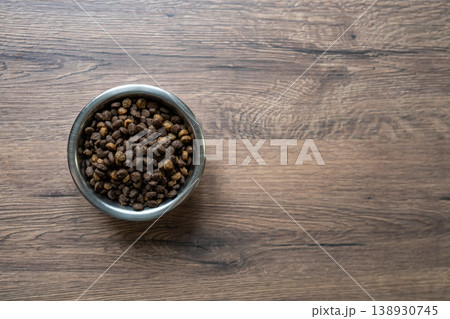 Cat dry food in metal bowl top view minimal wooden background Cat dry food in metal bowl top view minimal wooden background 138930745