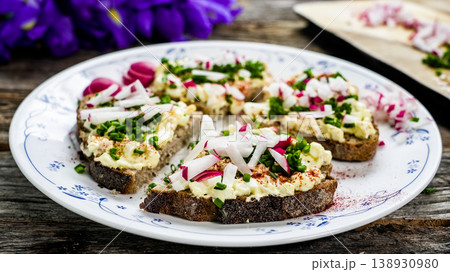 Egg salad open sandwiches with radish and chives on rye bread 138930980