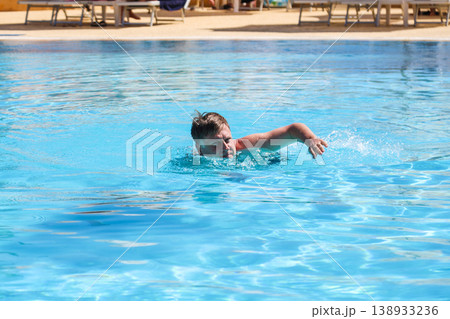 A man practices professional swimming in a hotel pool A man practices professional swimming in a hotel pool 138933236