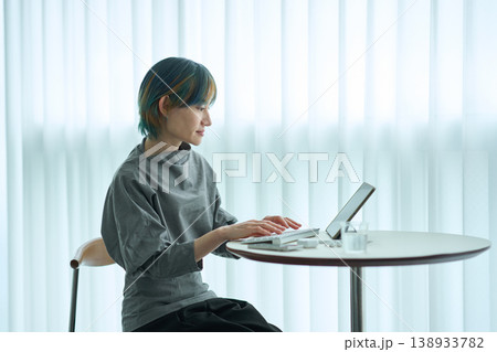 室内でタブレットを操作する金青カラーヘアの女性 138933782