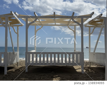 Beach cabana with wooden structure and view of ocean under cloudy sky, ideal as background 138934093