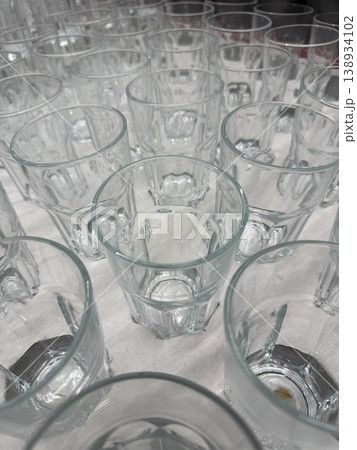 Empty glass cups arranged in neat rows creating transparent background pattern 138934102