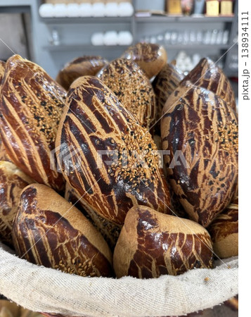 Freshly baked bread rolls with sesame seeds stacked in a basket at a bakery display Freshly baked bread rolls with sesame seeds stacked in a basket at a bakery display 138934111