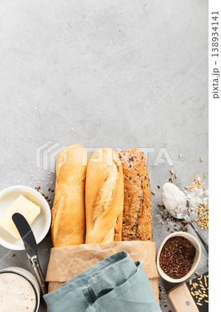 Assorted Baguettes with Butter, Flour, and Seeds on Table 138934141