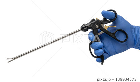 Gloved hand holding a long laparoscopic grasper or forceps with a ratcheted handle and jaw tip, isolated, representing minimally invasive surgery and operating room instruments Gloved hand holding a long laparoscopic grasper or forceps with a ratcheted handle and jaw tip, isolated, representing minimally invasive surgery and operating room instruments 138934375