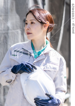 作業服を着てヘルメットを持つ笑顔の女性作業員 工事現場 建設業 スタッフ ポートレート 138934629