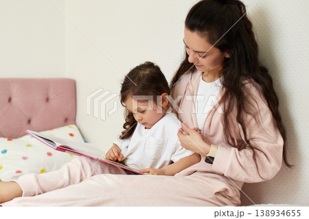 Young mother spending quality time with her child, reading a bedtime story together at home. Family bonding and education concept Young mother spending quality time with her child, reading a bedtime story together at home. Family bonding and education concept 138934655