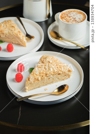 Sliced Napoleon cake on a white wooden table. Classic dessert Sliced Napoleon cake on a white wooden table. Classic dessert 138934704