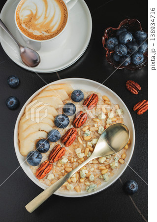 Oatmeal. Bowl of oatmeal porridge with blackberry, bananas and chia seeds on gray concrete old table background. Top view in flat lay style. Natural ingredients. Hot healthy breakfast and diet food Oatmeal. Bowl of oatmeal porridge with blackberry, bananas and chia seeds on gray concrete old table background. Top view in flat lay style. Natural ingredients. Hot healthy breakfast and diet food 138934716