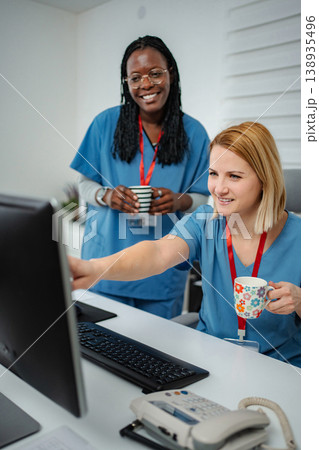 Nurses collaborating looking at computer screen in clinic Nurses collaborating looking at computer screen in clinic 138935496