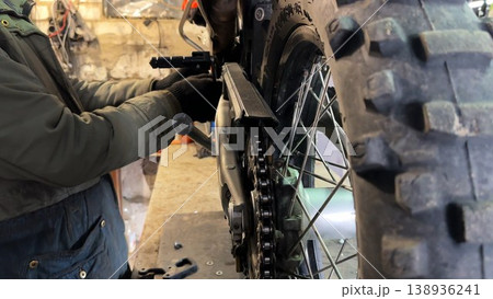 Professional mechanic repairing detail of motorcycle at workplace. Male repairer fixing moto at workshop. Adult repairman mending vehicle at garage. Concept of maintenance service. Slow motion 138936241
