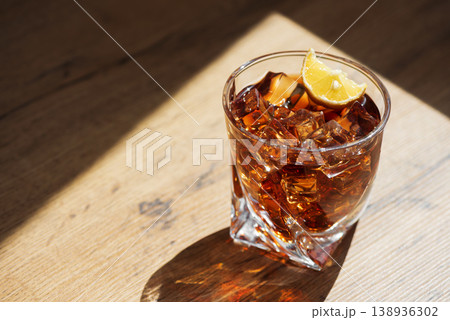 Cocktail with Whiskey, Cola and Lemon Garnish in Crystal Glass on Dark Wooden Background Cocktail with Whiskey, Cola and Lemon Garnish in Crystal Glass on Dark Wooden Background 138936302