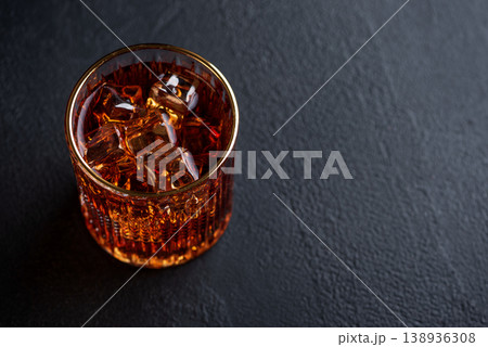 Whiskey Glass with Ice on Wooden Coaster against Dark Concrete Background Whiskey Glass with Ice on Wooden Coaster against Dark Concrete Background 138936308