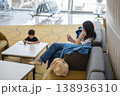 Woman Using Smartphone While Child Engages with Tablet in Modern Airport Lounge 138936310