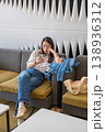 Young Woman Relaxing on Couch While Using Smartphone in Modern Lounge Setting 138936312