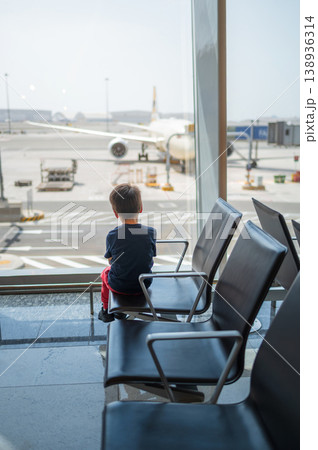Young Boy Watching Airplane at Airport Terminal Window 138936314