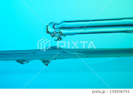 Pipette dripping liquid drop on turquoise water surface 138936741