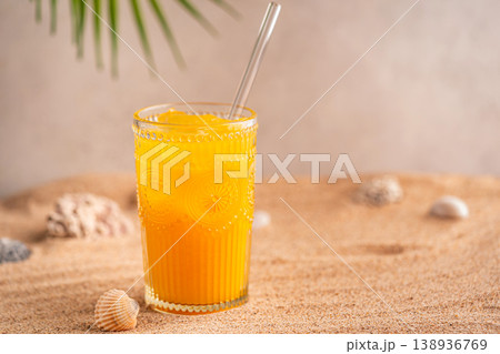 Colourful orange cocktail in a tall glass on a sand Colourful orange cocktail in a tall glass on a sand 138936769