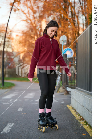 Young female athlete gliding on inline skates in neighborhood setting, natural full body portrait at golden hour. Ideal for active living, recreation, mobility or fitness promotion 138936787