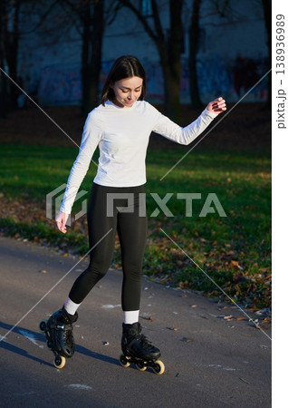 Female skater balancing on inline boots in park, calm candid moment during recreational ride. Suitable for hobby, fitness, self care or healthy routine messages Female skater balancing on inline boots in park, calm candid moment during recreational ride. Suitable for hobby, fitness, self care or healthy routine messages 138936989