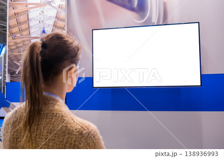 Woman looking at blank white display wall at exhibition - white screen concept Woman looking at blank white display wall at exhibition - white screen concept 138936993