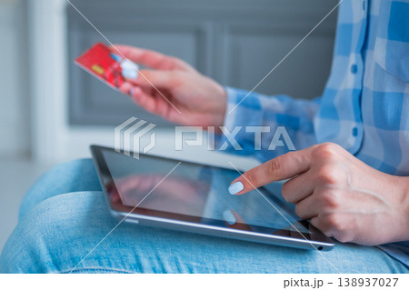 Woman using black tablet and red credit card for online shopping at home Woman using black tablet and red credit card for online shopping at home 138937027