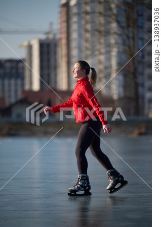 Female skater enjoying calm winter day on urban lake ice with copy space around her. Useful for advertising layouts, recreation concepts, fitness content or editorial design 138937036