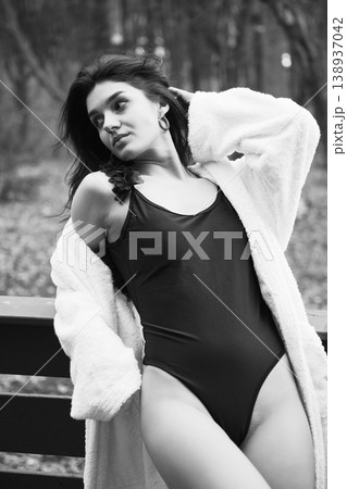 Elegant woman in swimsuit and bathrobe relaxing on terrace, holding champagne glass. Black and white portrait conveying luxury, wellness lifestyle, calm mood and refined leisure Elegant woman in swimsuit and bathrobe relaxing on terrace, holding champagne glass. Black and white portrait conveying luxury, wellness lifestyle, calm mood and refined leisure 138937042