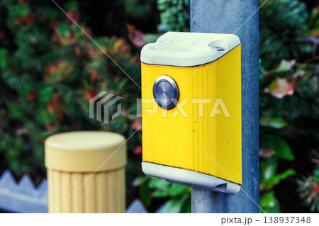 Close up of a yellow pedestrian crossing push button mounted on a pole. Urban street infrastructure 138937348